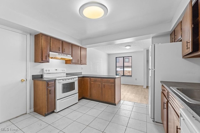 kitchen with white appliances, kitchen peninsula, and light tile patterned flooring