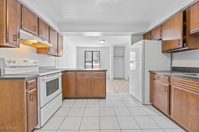 kitchen with light tile patterned floors, white appliances, and kitchen peninsula