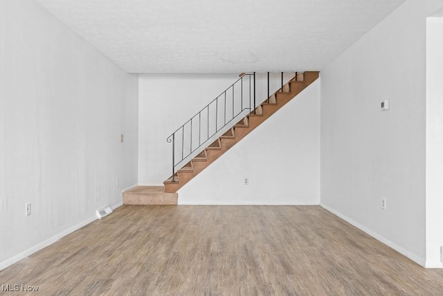 unfurnished living room featuring hardwood / wood-style floors and a textured ceiling