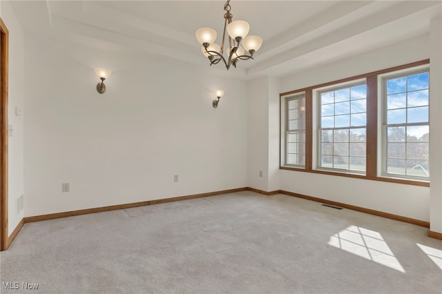 carpeted spare room with a notable chandelier and a tray ceiling