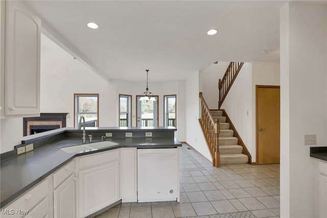 kitchen with sink, hanging light fixtures, light tile patterned floors, dishwasher, and white cabinets