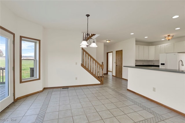 kitchen featuring white cabinetry, white refrigerator with ice dispenser, pendant lighting, and light tile patterned floors