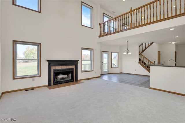 unfurnished living room featuring a high ceiling, a tile fireplace, and light colored carpet