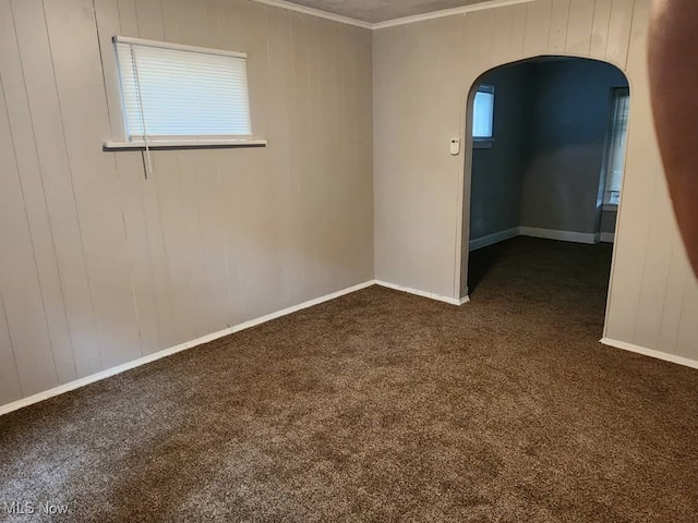 empty room featuring ornamental molding and dark colored carpet