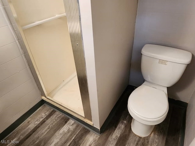 bathroom featuring a shower, hardwood / wood-style floors, and toilet