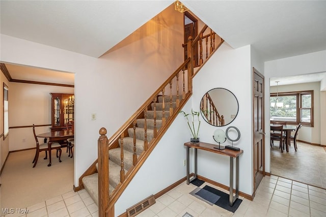 stairway featuring an inviting chandelier and carpet flooring