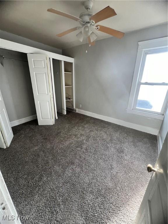 unfurnished bedroom featuring dark carpet and ceiling fan