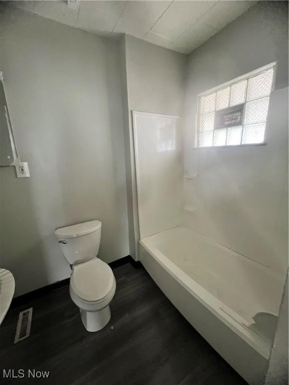 bathroom featuring wood-type flooring, walk in shower, and toilet