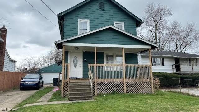 bungalow-style house with a garage, an outdoor structure, covered porch, and a front lawn