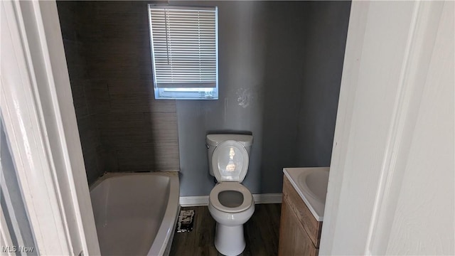 bathroom with vanity, a tub, hardwood / wood-style floors, and toilet