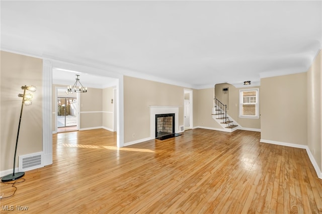 unfurnished living room with an inviting chandelier and light wood-type flooring