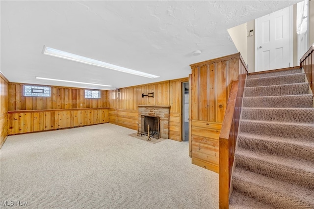 basement featuring a stone fireplace, light carpet, and wood walls