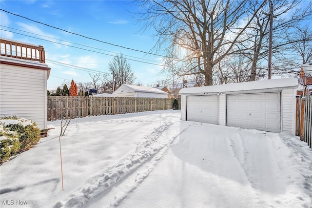 snowy yard with a garage and an outdoor structure