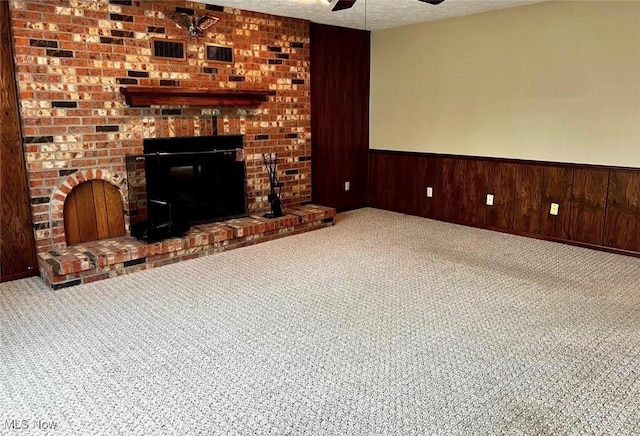 carpeted cinema featuring ceiling fan, a brick fireplace, a textured ceiling, and wood walls