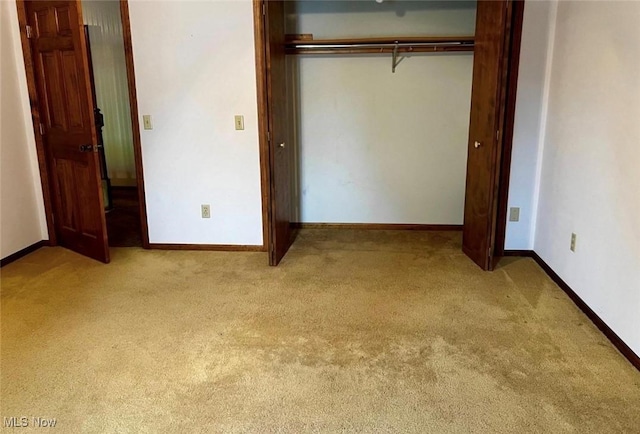 unfurnished bedroom with light colored carpet and a closet