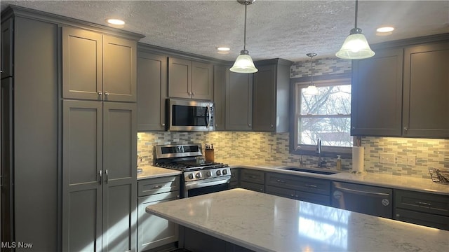 kitchen featuring appliances with stainless steel finishes, gray cabinets, a sink, and light stone counters