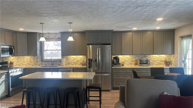 kitchen featuring sink, hanging light fixtures, stainless steel appliances, light hardwood / wood-style floors, and a kitchen island