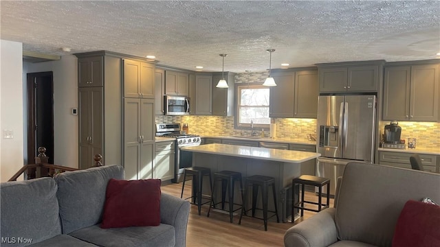 kitchen featuring pendant lighting, gray cabinetry, a kitchen breakfast bar, a center island, and stainless steel appliances