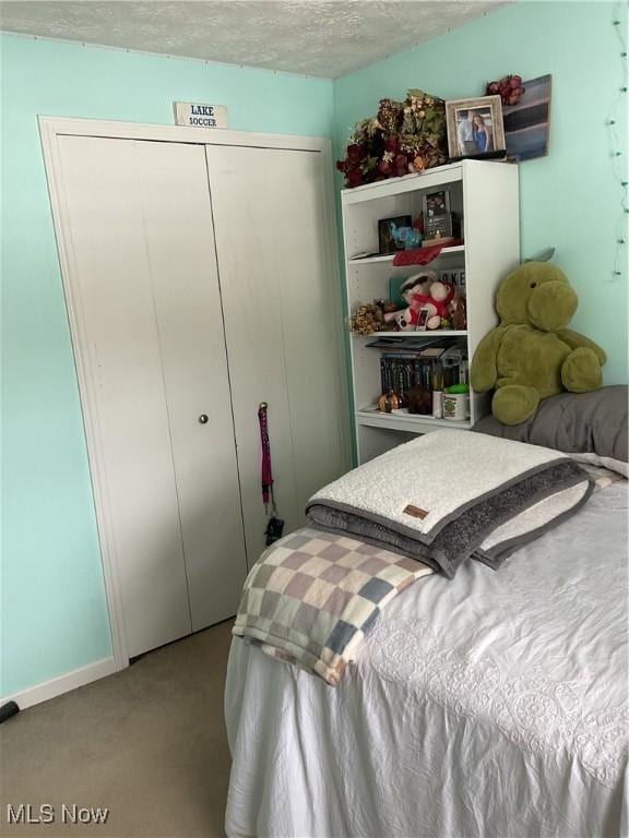 carpeted bedroom with a closet and a textured ceiling