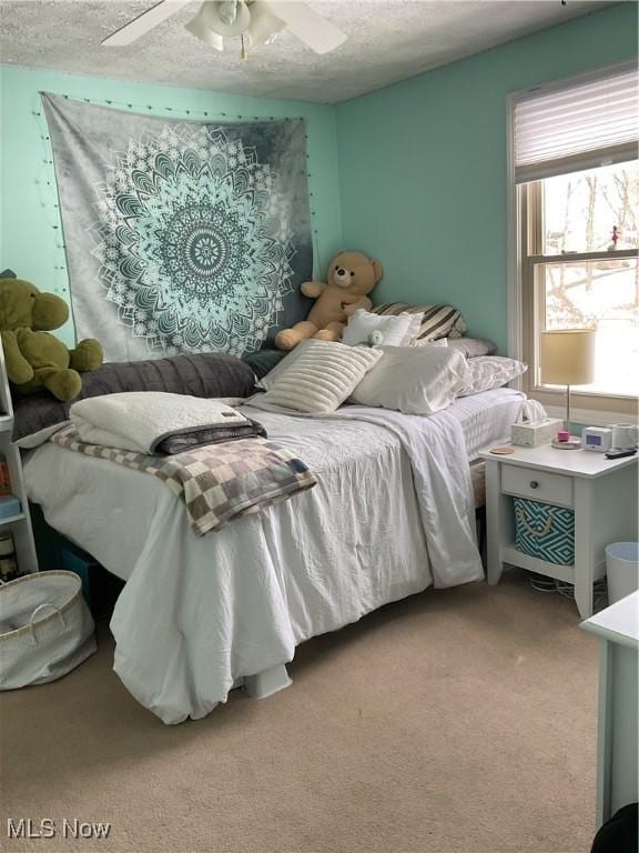 carpeted bedroom featuring ceiling fan and a textured ceiling