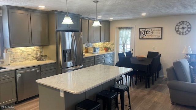 kitchen featuring a center island, dark wood-style flooring, a breakfast bar area, appliances with stainless steel finishes, and open floor plan