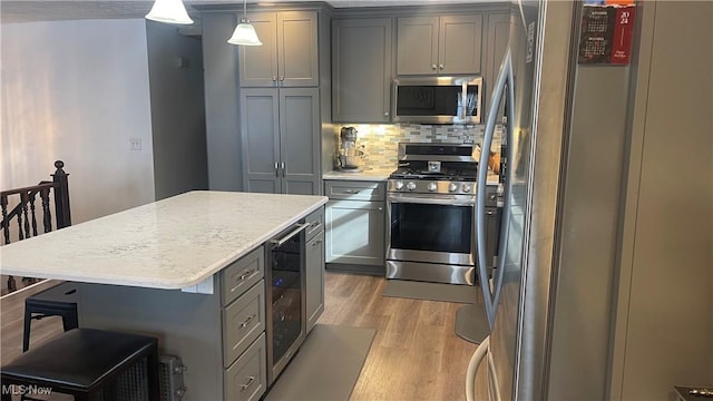 kitchen featuring stainless steel appliances, decorative light fixtures, a center island, and gray cabinetry