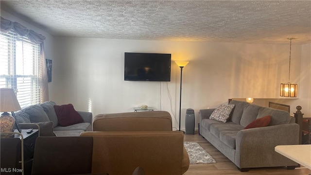 living room featuring an inviting chandelier, hardwood / wood-style floors, and a textured ceiling