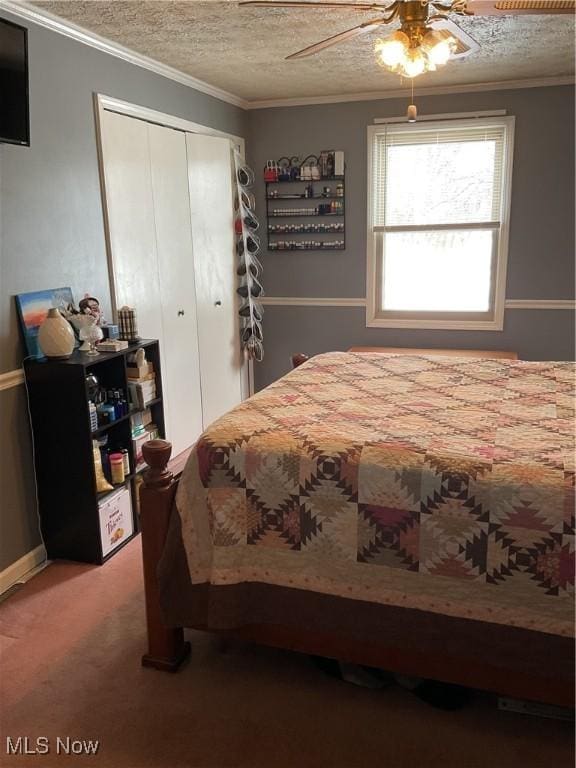 bedroom with carpet floors, ornamental molding, ceiling fan, a textured ceiling, and a closet