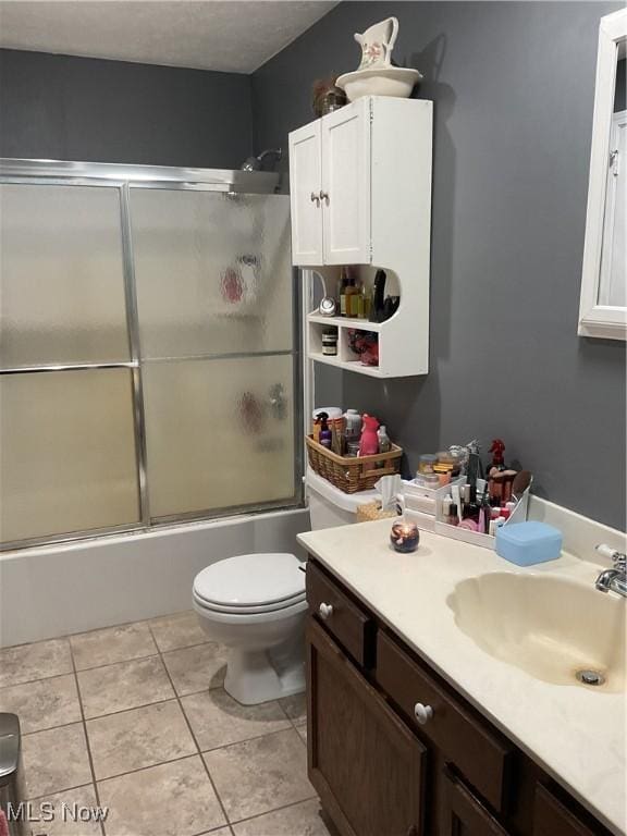 full bathroom featuring toilet, bath / shower combo with glass door, vanity, and tile patterned floors