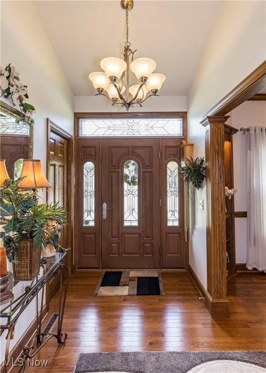 foyer entrance featuring dark wood-type flooring, a notable chandelier, and high vaulted ceiling