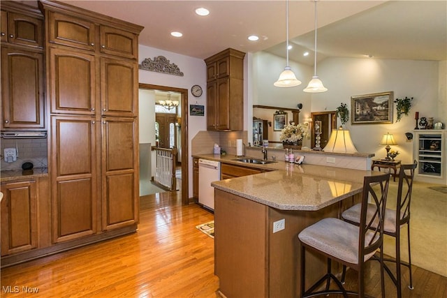 kitchen with dishwasher, sink, backsplash, a kitchen breakfast bar, and kitchen peninsula