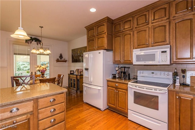 kitchen with light stone counters, decorative light fixtures, light hardwood / wood-style flooring, a notable chandelier, and white appliances