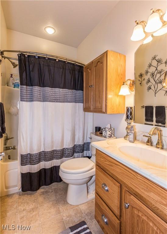 full bathroom with shower / tub combo with curtain, vanity, tile patterned floors, and toilet