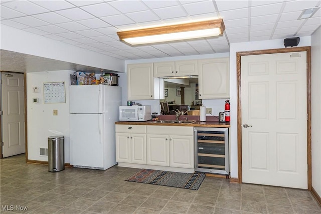 kitchen featuring a paneled ceiling, wood counters, sink, wine cooler, and white appliances