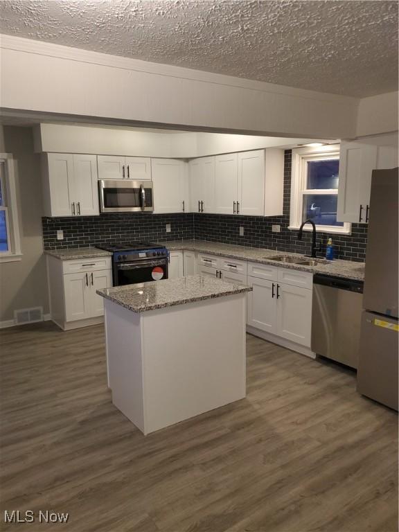 kitchen featuring visible vents, stainless steel appliances, dark wood-type flooring, and a sink