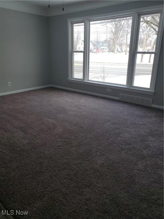 unfurnished room with crown molding, baseboards, visible vents, and dark carpet