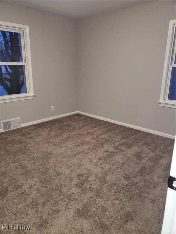 carpeted spare room featuring baseboards and visible vents