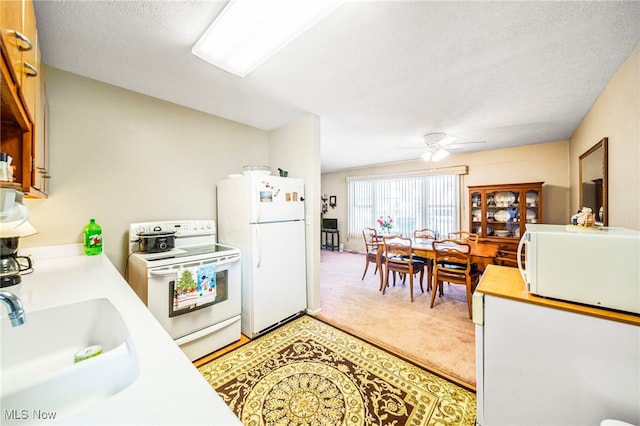 kitchen featuring sink, white appliances, a textured ceiling, carpet flooring, and ceiling fan