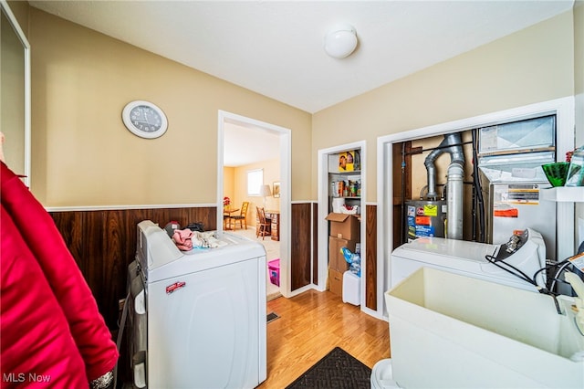 laundry room with gas water heater, washing machine and dryer, and light wood-type flooring