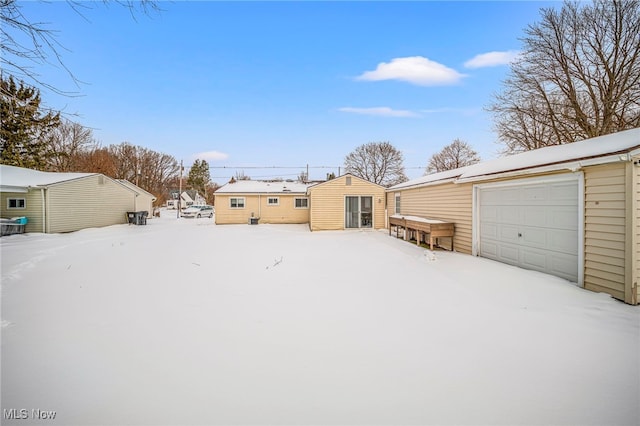 yard covered in snow with a garage and an outbuilding