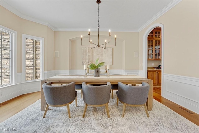 dining room featuring crown molding, a wealth of natural light, a chandelier, and light hardwood / wood-style flooring