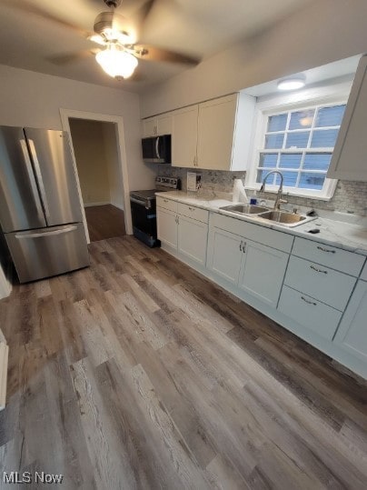 kitchen featuring stainless steel appliances, sink, white cabinets, and light wood-type flooring