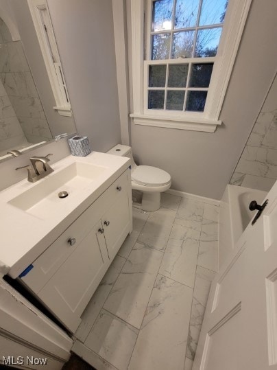 bathroom featuring vanity, a bath, and toilet