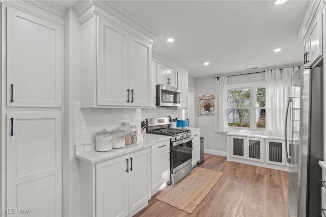 kitchen with white cabinetry, appliances with stainless steel finishes, light stone counters, and decorative backsplash