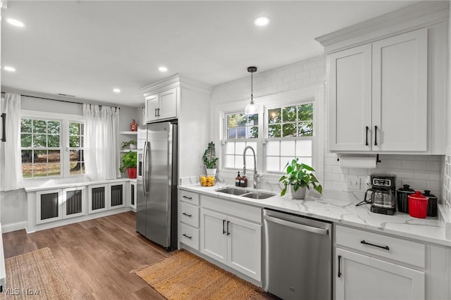 kitchen featuring pendant lighting, sink, white cabinetry, stainless steel appliances, and decorative backsplash