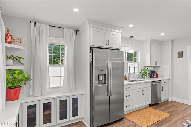 kitchen with decorative light fixtures, white cabinetry, sink, backsplash, and stainless steel appliances