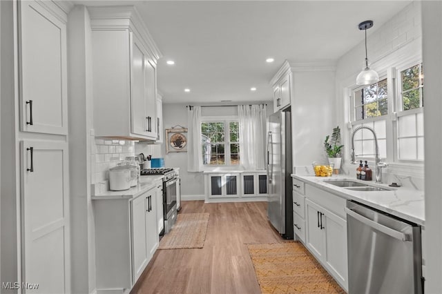 kitchen featuring white cabinetry, sink, stainless steel appliances, light stone countertops, and light hardwood / wood-style flooring