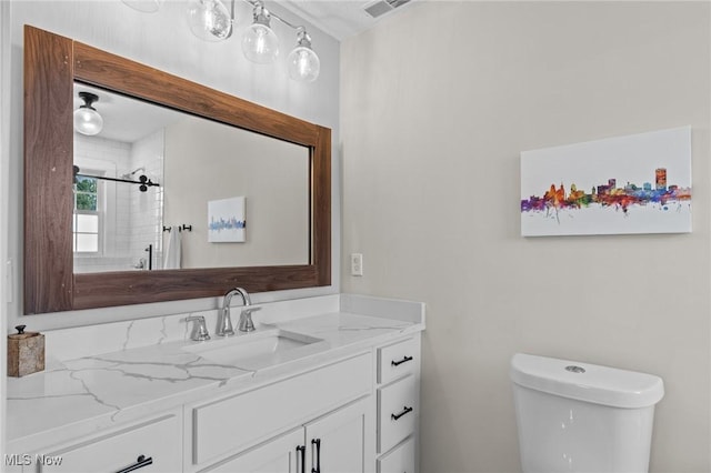 bathroom with tiled shower, vanity, and toilet