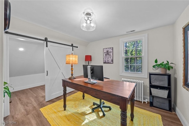 office area featuring radiator heating unit, a barn door, and wood-type flooring