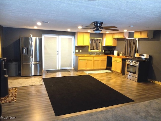 kitchen featuring light brown cabinetry, sink, light hardwood / wood-style floors, black appliances, and a textured ceiling